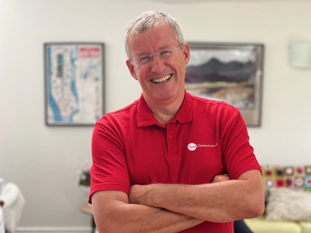 Tom Clendon standing with his arms crossed and a red polo shirt on.